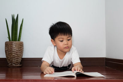 Cute boy sitting on table at home