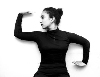 Woman looking away while standing against white background