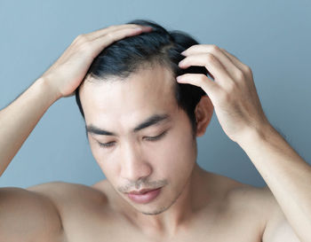 Portrait of shirtless man against blue background