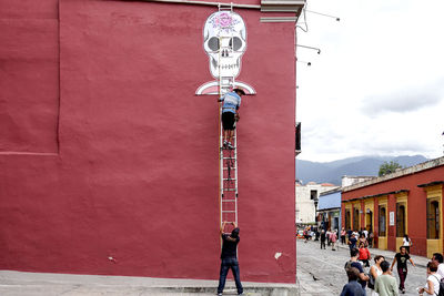 People walking on street by building against sky