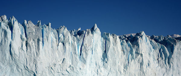 Panoramic view of frozen landscape against clear blue sky