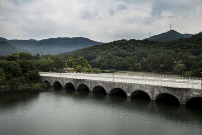 Arch bridge over river against sky