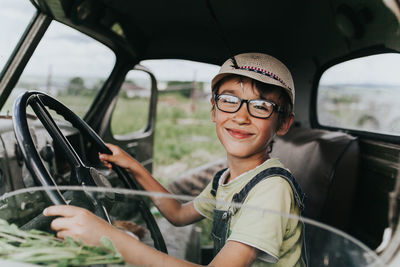 Portrait of boy holding steering wheel sitting in car