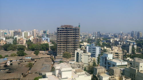 High angle view of slum and city against clear sky