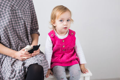 Portrait of boy using mobile phone while sitting against white background