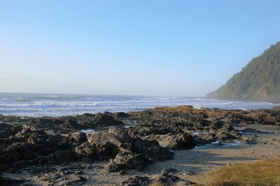 Rocks on beach against clear sky