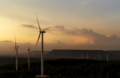 Windmills on field against sky during sunset