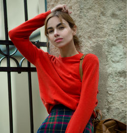 Portrait of beautiful young woman standing against wall