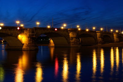 Illuminated bridge over river against sky at night