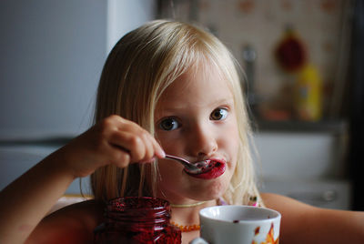 Close-up of cute girl eating jam at home