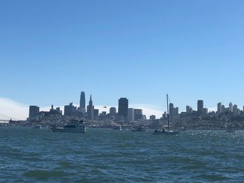 Sea by buildings against clear blue sky