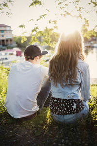 Rear view of teenage couple sitting at lakeshore