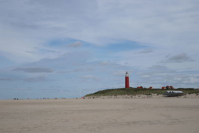 Lighthouse on beach against sky