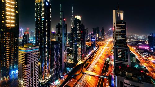 Light trails on road amidst buildings in city at night