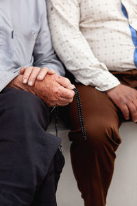 Midsection of men sitting side by side on seat