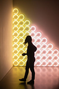 Silhouette woman standing against illuminated lights