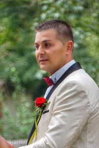 Portrait of young man standing on red flowering plant