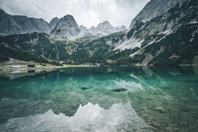 Scenic view of lake by snow mountains against sky