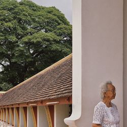 Rear view of woman standing on roof against trees