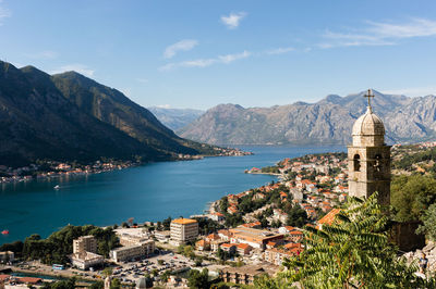 High angle view of town by sea and mountains against sky