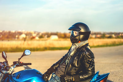 Man wearing black jacket sitting on motorcycle during sunset