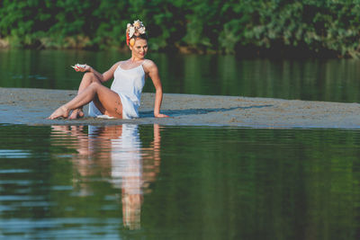 Full length of woman sitting by lake