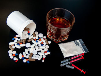 High angle view of drugs and drink over black background
