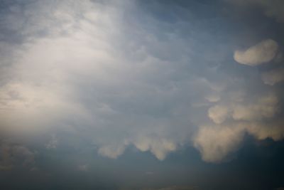 Low angle view of sunlight streaming through clouds