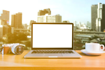 Coffee cup and laptop on table