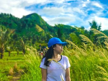 Young woman looking away while standing on field