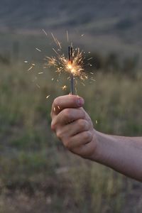 Cropped hand holding illuminated sparkler