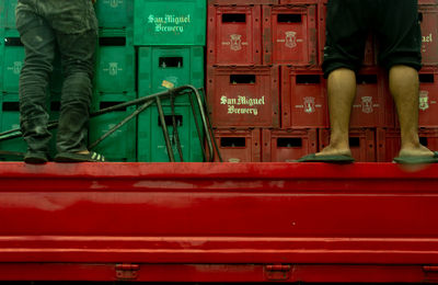 Low section of men standing on truck against crates