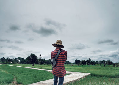 Rear view of man standing on field against sky