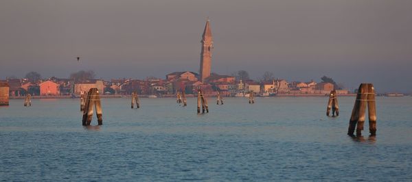 Scenic view of burano  by sea during sunset