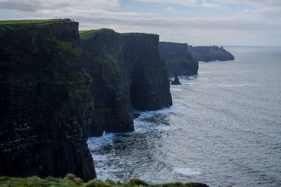 Scenic view of sea by cliff against sky