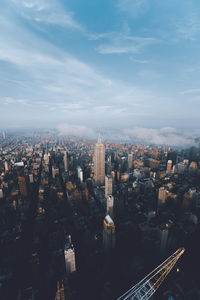 Aerial view of city buildings against cloudy sky