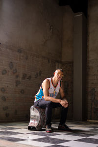 Young woman looking away while sitting on building wall