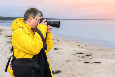 Man photographing while standing on beach