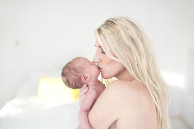 Woman kissing newborn daughter