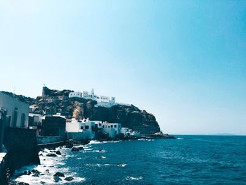 Buildings by sea against clear sky