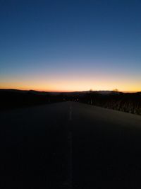 Empty road against clear sky during sunset