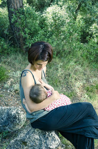 High angle view of mother and daughter sitting on tree