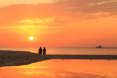 Silhouette people on beach against sky during sunset