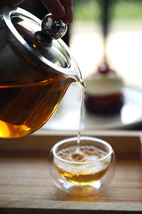 Close-up of hand pouring tea in cup on table