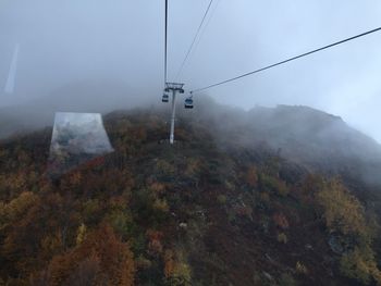 Overhead cable car over mountains against sky