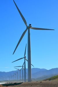 Low angle view of windmill on field against clear blue sky