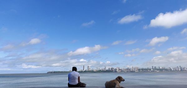Rear view of people with dog on sea against sky