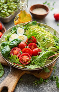 Fresh summer salad with arugula, red cherry tomatoes, basil, eggs and avocado. vegan food. 