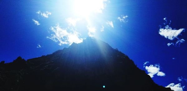 Low angle view of silhouette mountain against sky on sunny day
