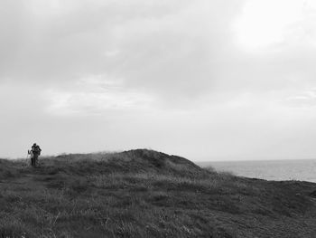 Man standing on field by sea against sky